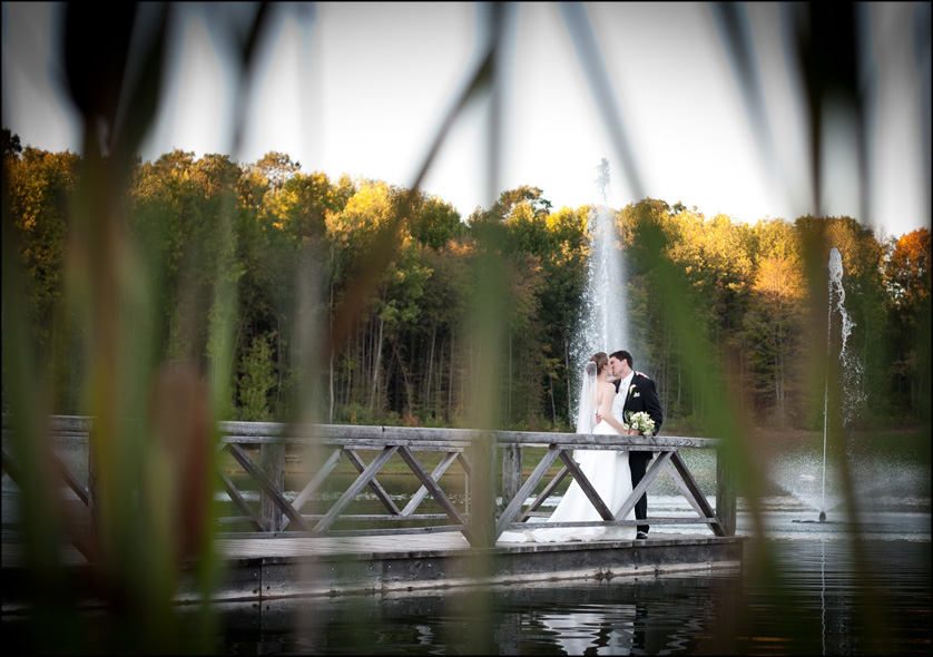 Married couple are seen through tall weeds on a bridge at The Lodge at Bear Creek by the fountain