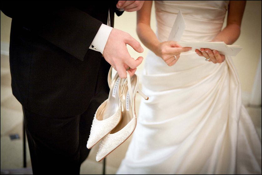 groom holds white shoes and bride holds cards
