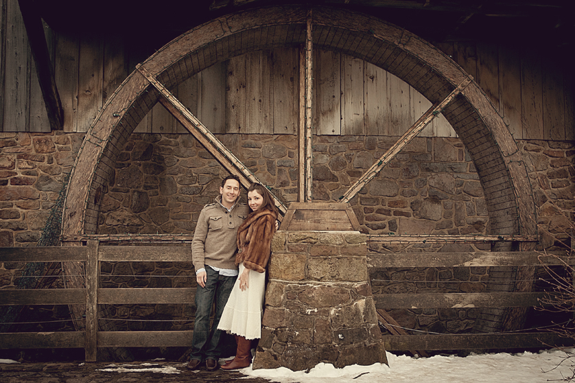 Couple standing in front of water wheel at mill in Peddlers village