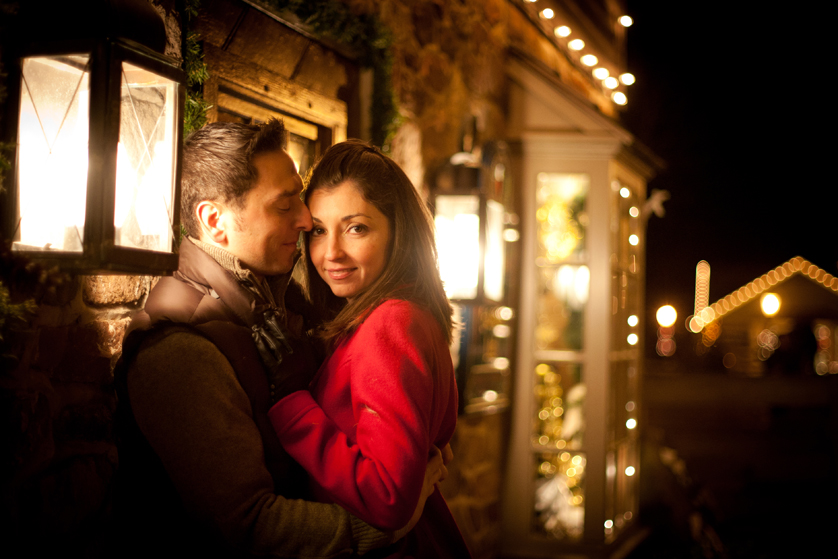 Warm glow of christmas lights for engagement photo at Peddlers Village
