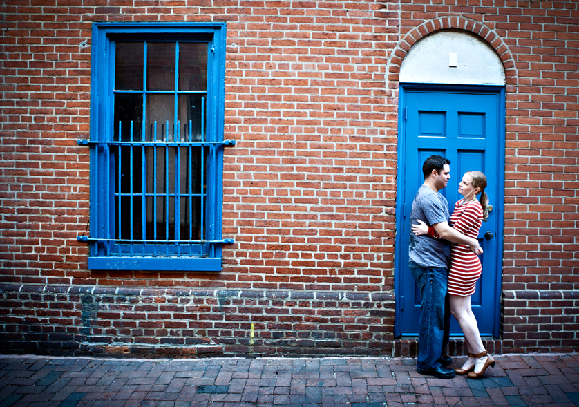 Urban engagement photo of couple in front of bright blue door and brick wall