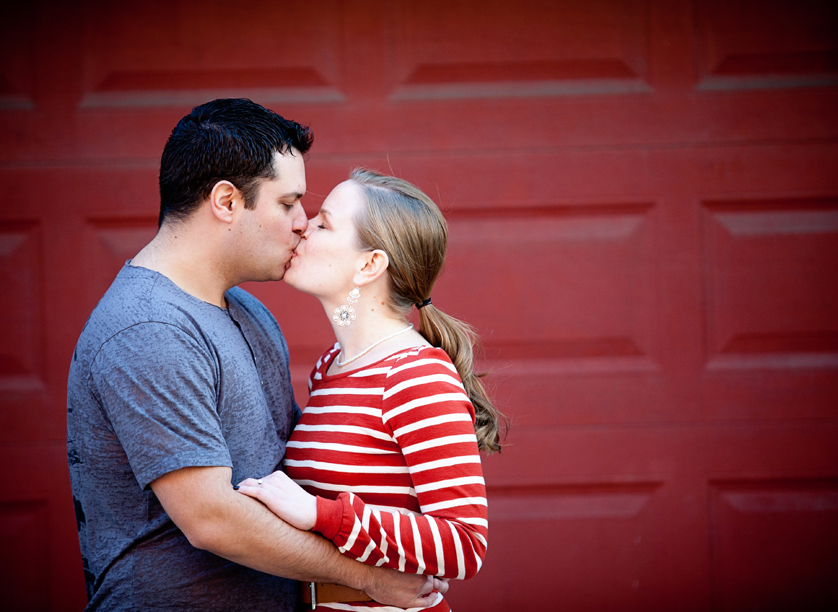 Kissing couple framed by red wall in Philadelphia, PA