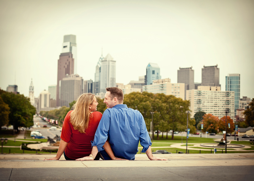 Couple sitting at top of Art Museum steps with Philadelphia skyline behind them