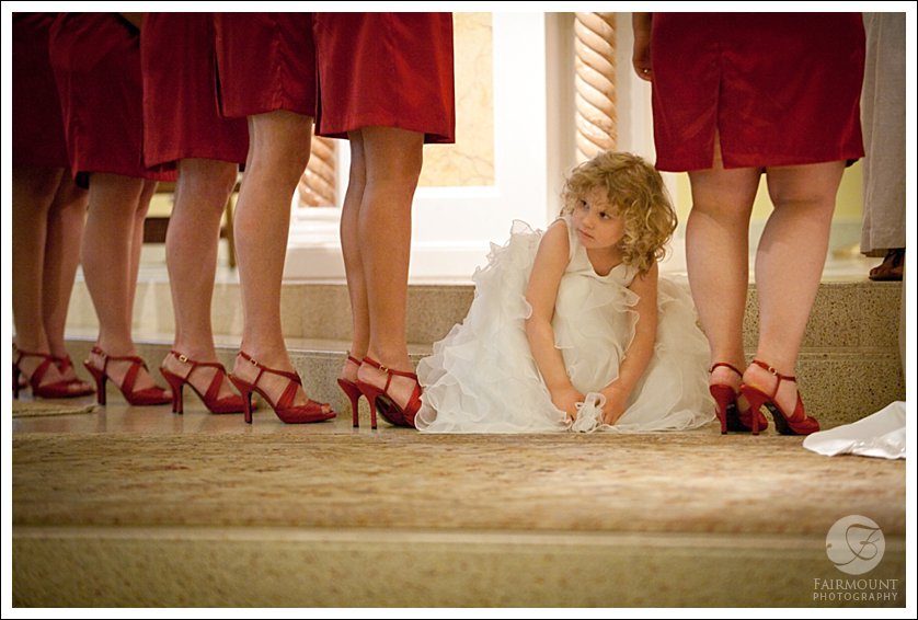 flower girl peeks out between legs of bridesmaids