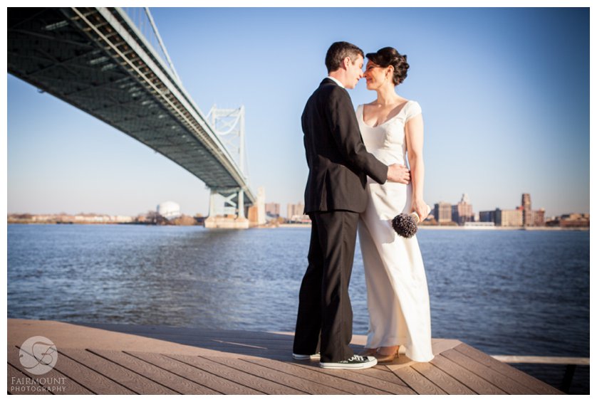 The Ben Franklin bridge stretches out behind Bride & Groom