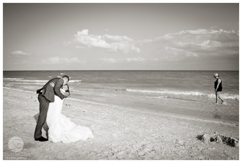 a beach walker passes by bride and groom in Sanibel Island, Florida