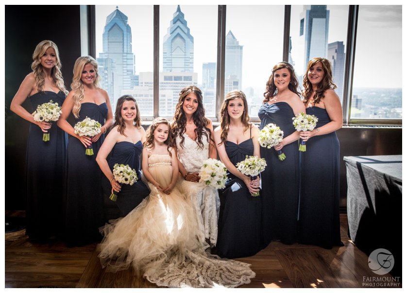bride & bridesmaids on top floor of Loews hotel with Philadelphia skyline behind them