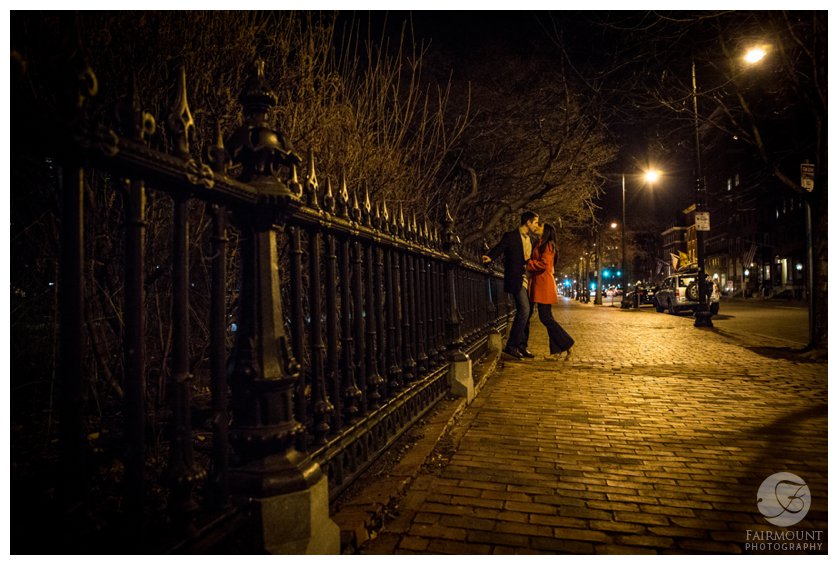 Engagement photo by wrought iron gate around the Boston Public Garden at night