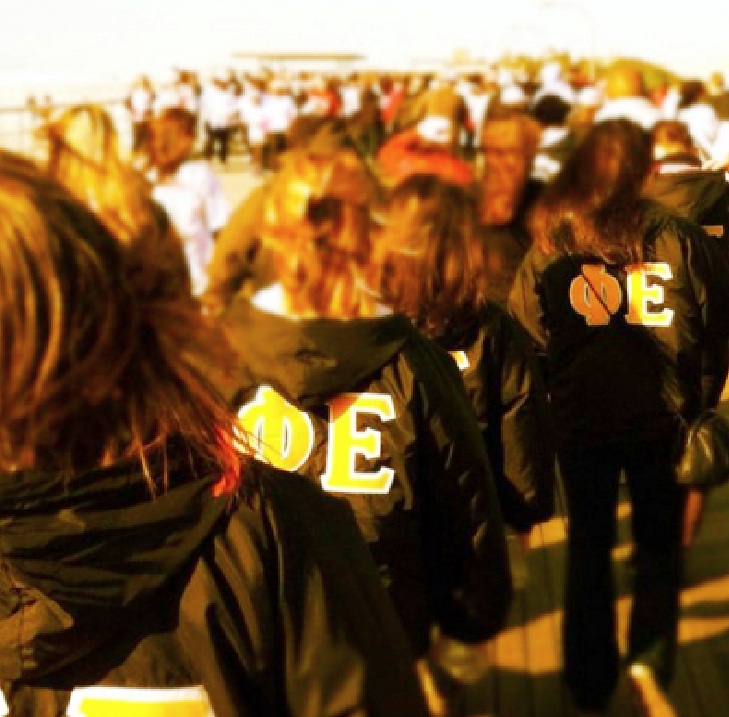 Phi Epsilon, donning their black and gold jackets, on the boardwalk at Jones Beach. Photo courtesy of Phi Epsilon's Twitter.