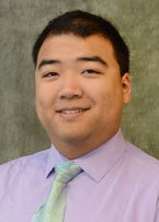 A headshot of Dr. Lee in front of a olive grey backdrop.