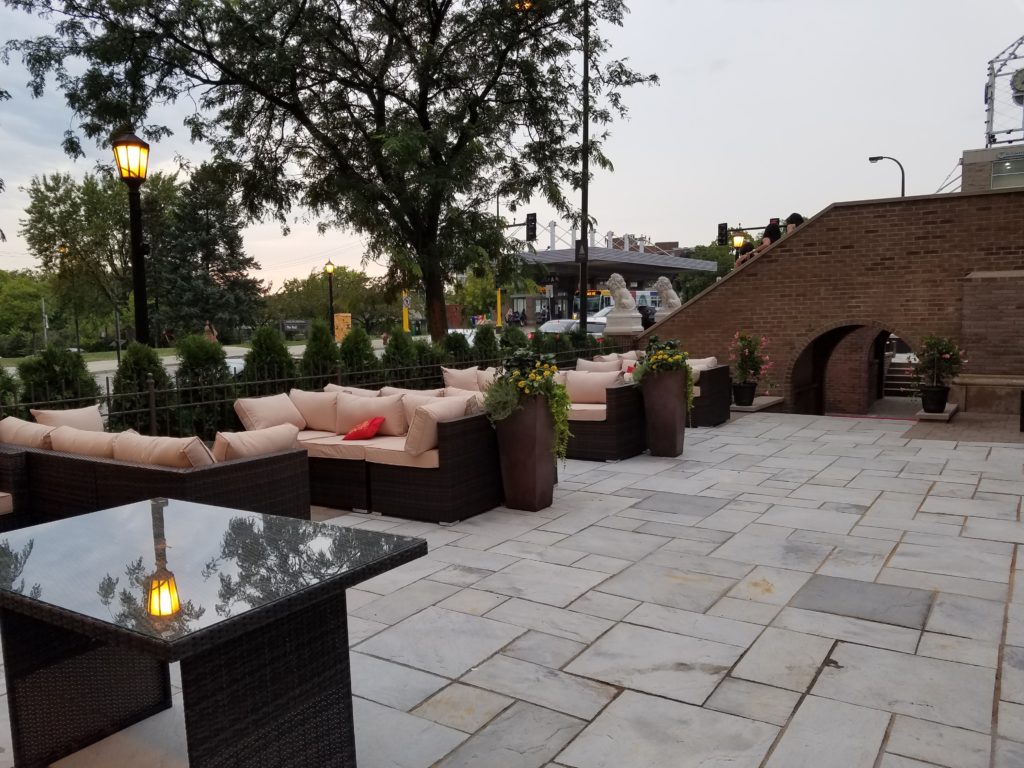 Mansion at Uptown Exterior Street Level Patio with couches, tables, and brick archway