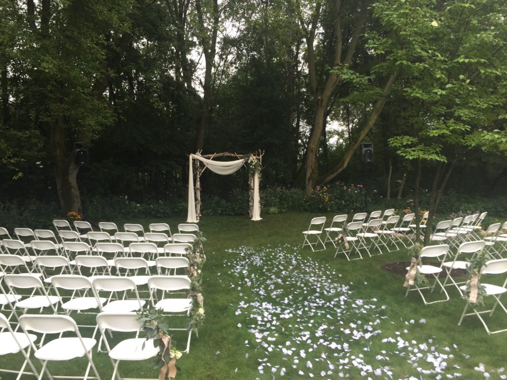 Picture of outdoor wedding with a rose petal aisle, archway, and AV for You speakers