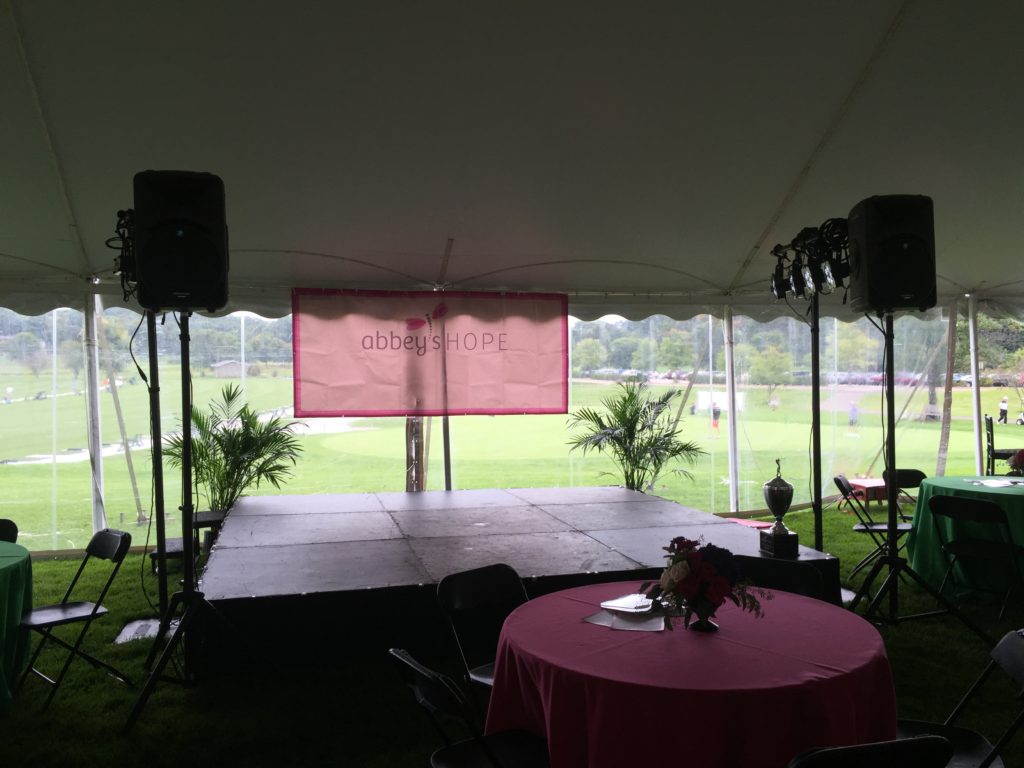 Picture of the stage with an Abbey's Hope banner and AV for You lighting and speakers