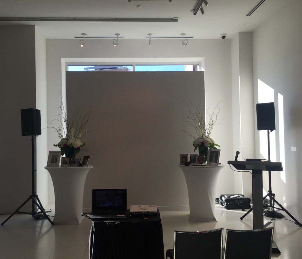 Picture of AV for You audio visual equipment set-up for a wedding at Le Meridien Chambers Minneapolis. Picture shows AV for You two k10s speakers with stands, a 4 channel mixer, 2 lavalier mics, a wired mic, and a 3k projector with stand and laptop.