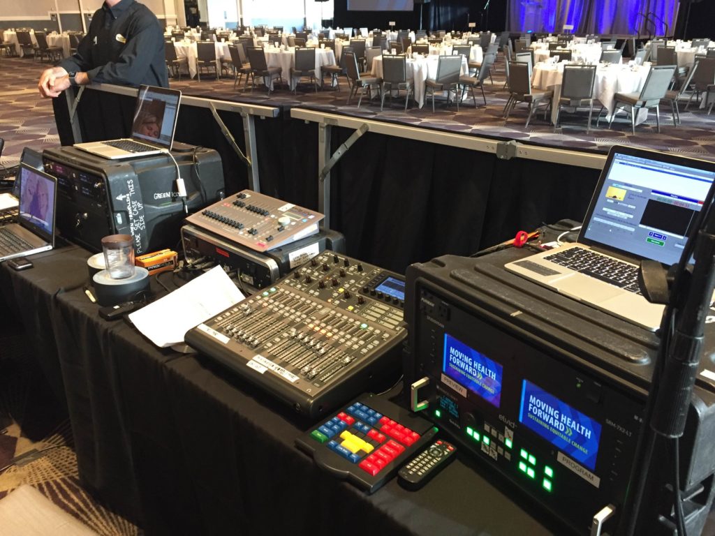 Picture of AV for You Rental Blue Cross Blue Shield Minnesota Luncheon at Intercontinental Hotel tech table set-up , featuring our Analog Way Video Switcher, Playback Pro laptop for a short video clip, Behringer X32 producer digital mixer for audio, Smartfade lighting console and Shure QLXD4 distro wireless microphone rack