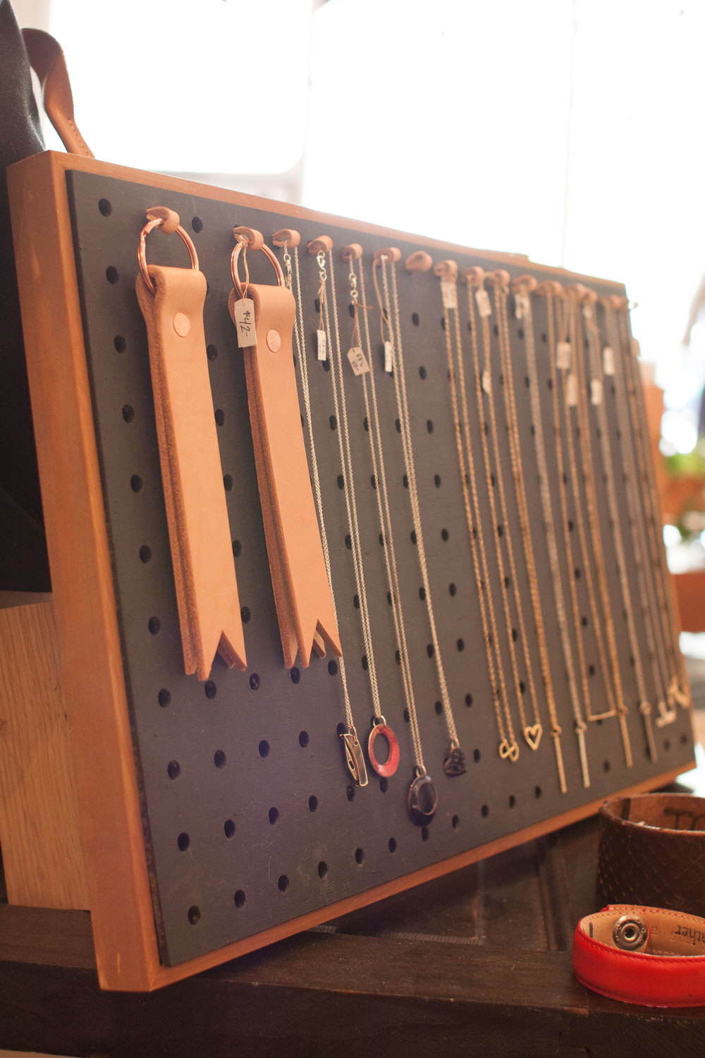  Various handmade pieces of jewelry are organized by small leather straps Chika made to attach to pegboard. It's the little things.  