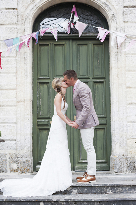 Bride and groom kissing outside the doors of the château