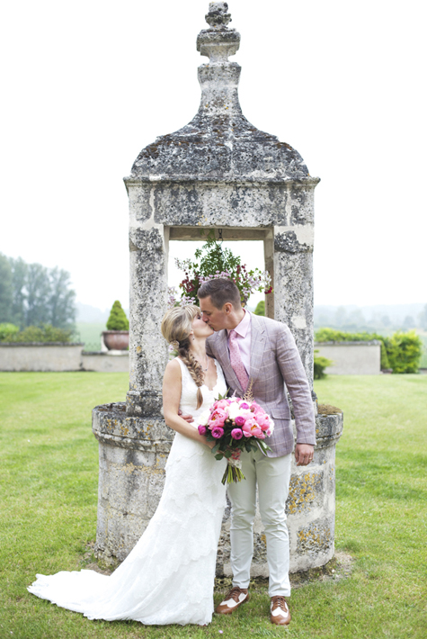 Bride and groom kissing by an old well