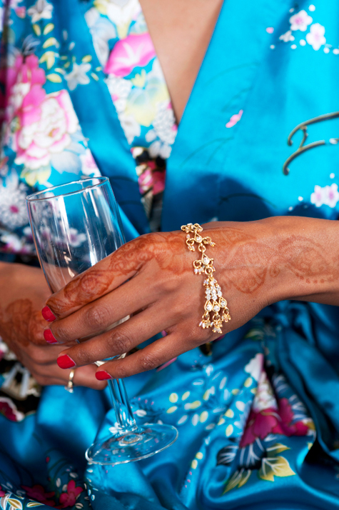 Detail shot of henna tattooed hand and bracelet holding glass