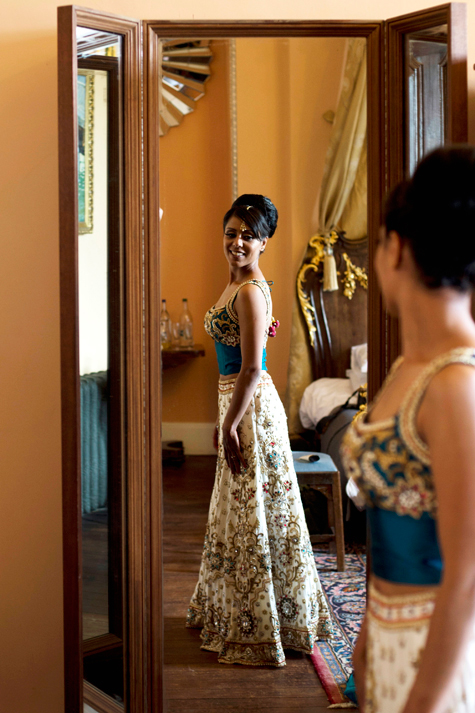 Full-length shot of bride smiling reflected in mirror in wedding outfit