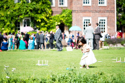 Exterior shot of guests and little girl with croquet stick on the lawn
