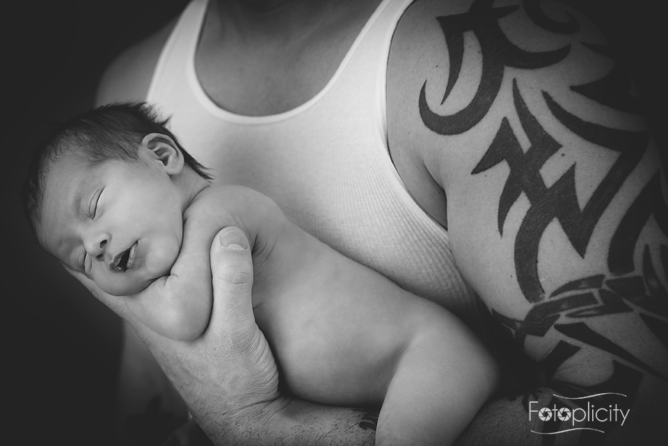 Tattooed arm holding infant newborn