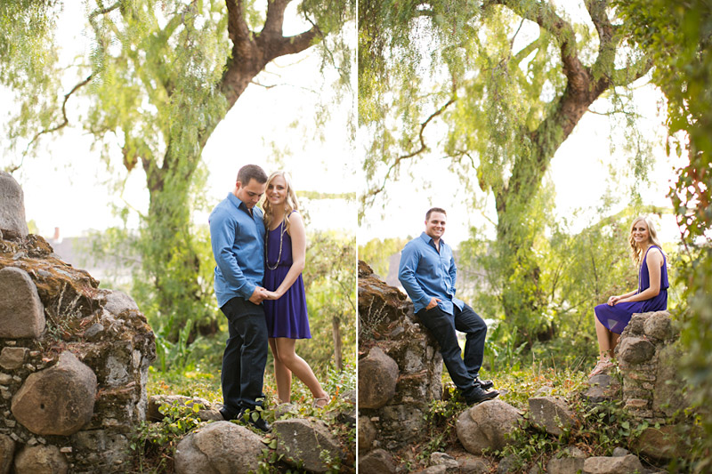 San Luis Obispo Engagement pictures of couple holding hands on a historic old mission wall surrounded by trees. 