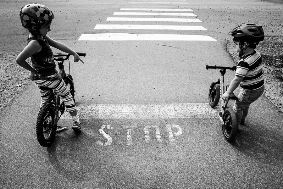 big sister telling brother to stop at the stop sign with his bike