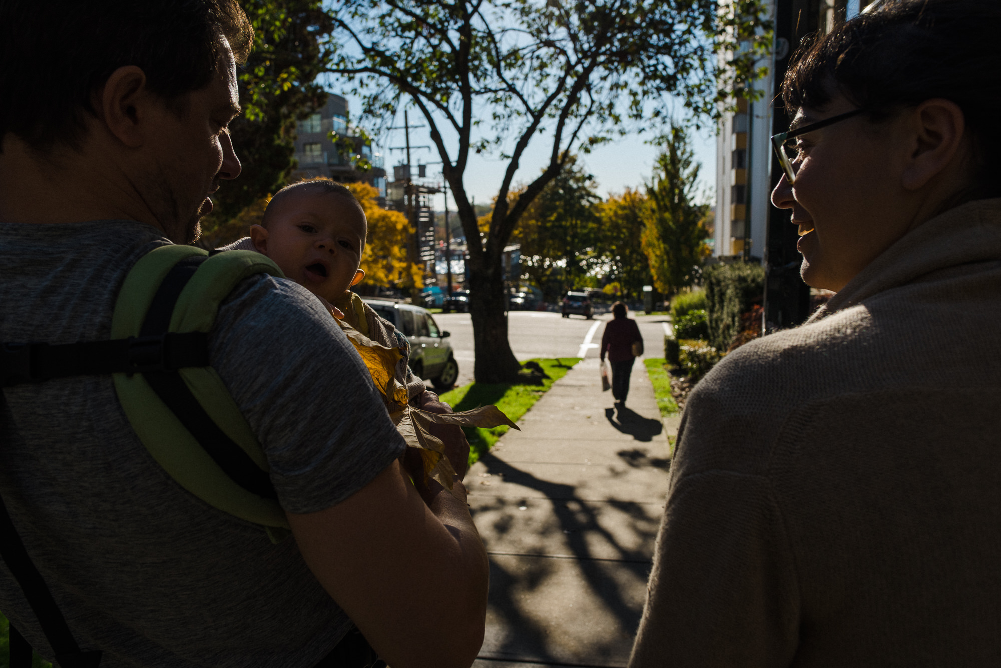 couple walking down the vancouver street while dad is wearing his baby in a carrier