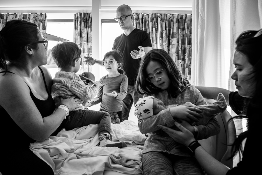 family visiting newborn baby boy in hospital maternity room