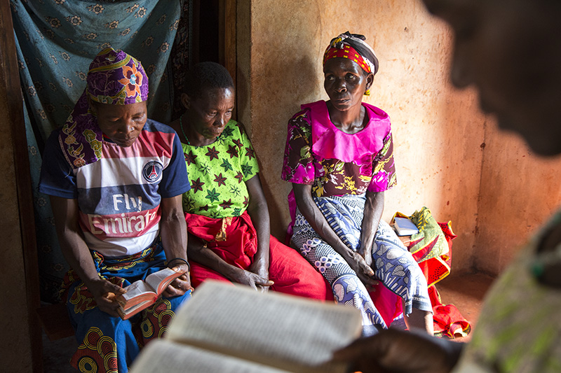 Berta Mapunda, back from left, Cosma Komba, and Wilfirda Ngonyani, listen as their friend Gertruda Domayo reads from her bible in Nakahegwa, Tanzania. Using a wide-angle lens to get closer helps an audience enter a story and feel more connected to the people in an image. Photo Courtesy of Sara A. Fajardo/Catholic Relief Services