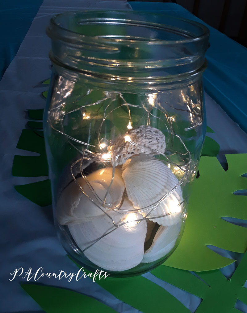 Seashells and fairy lights as a beach themed centerpiece!