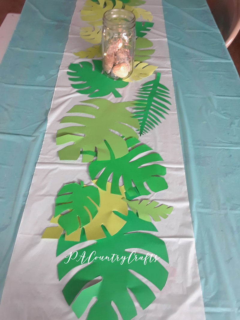 Easy decorations for a beach birthday party or tropical luau... cut out leaves from cardstock as a table runner.