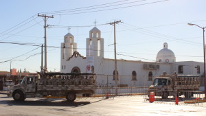 Soldiers in the Mexican Army pass by a church on Juarez's main thoroughfare