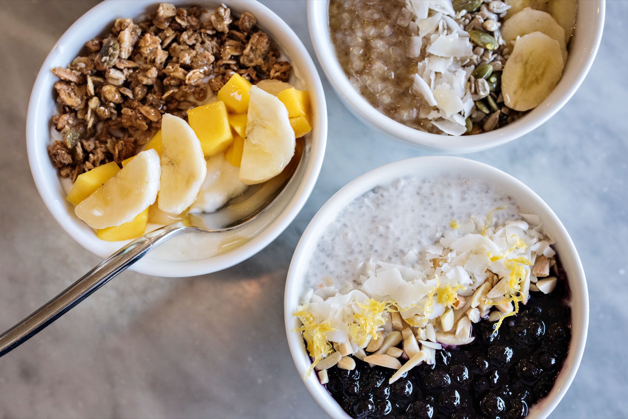 L to R: Müsli B with seasonal fruit / Quinoa Porridge with coconut flakes, toasted seeds and banana / Coconut Chia Seed Pudding with coconut flakes, crushed almonds, and blueberry-lemon compote / Photo by D'Ann McCormick Boal