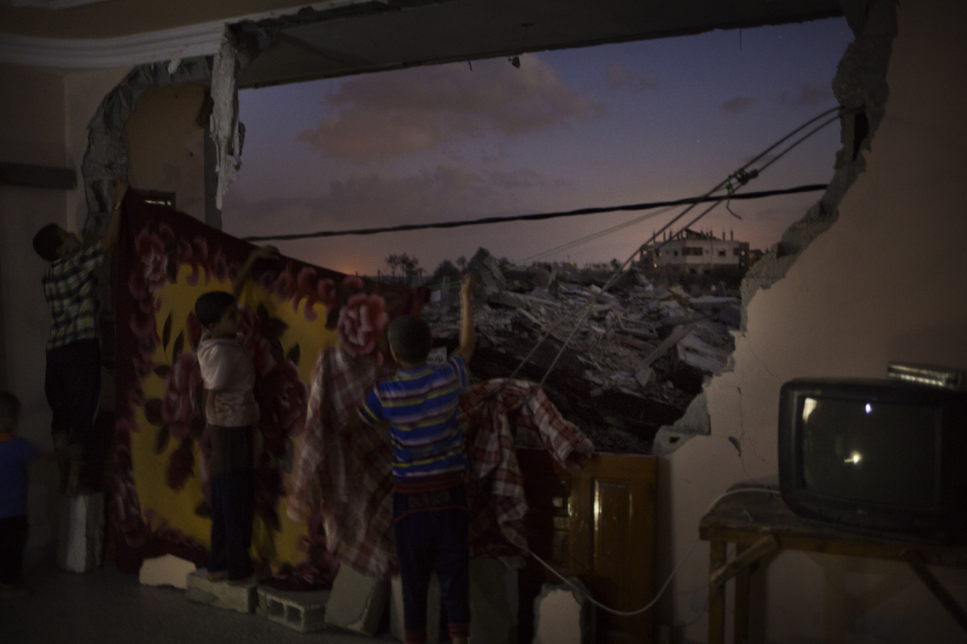 The family Harara has a three story house with four apartments. One of them is completely destroyed by the war in Gaza during the war in 2014. Each night the children cover up the destroyed wall so that they are able to sleep. 