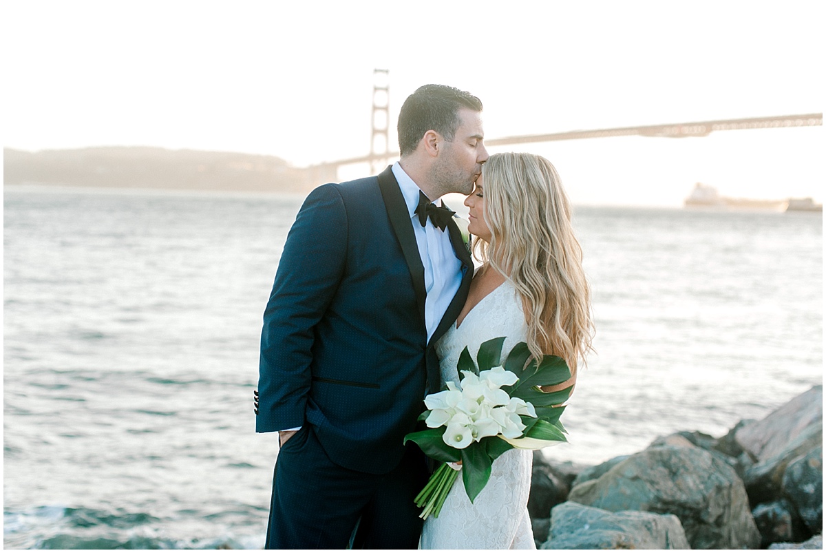 Gorgeous wedding at Presidio Yacht Club groom kissing bride on the forehead at sunset