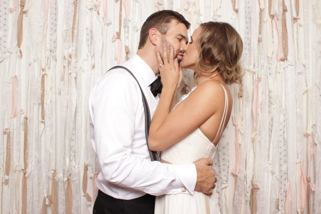 A bride and groom steal a kiss in their wedding photo booth