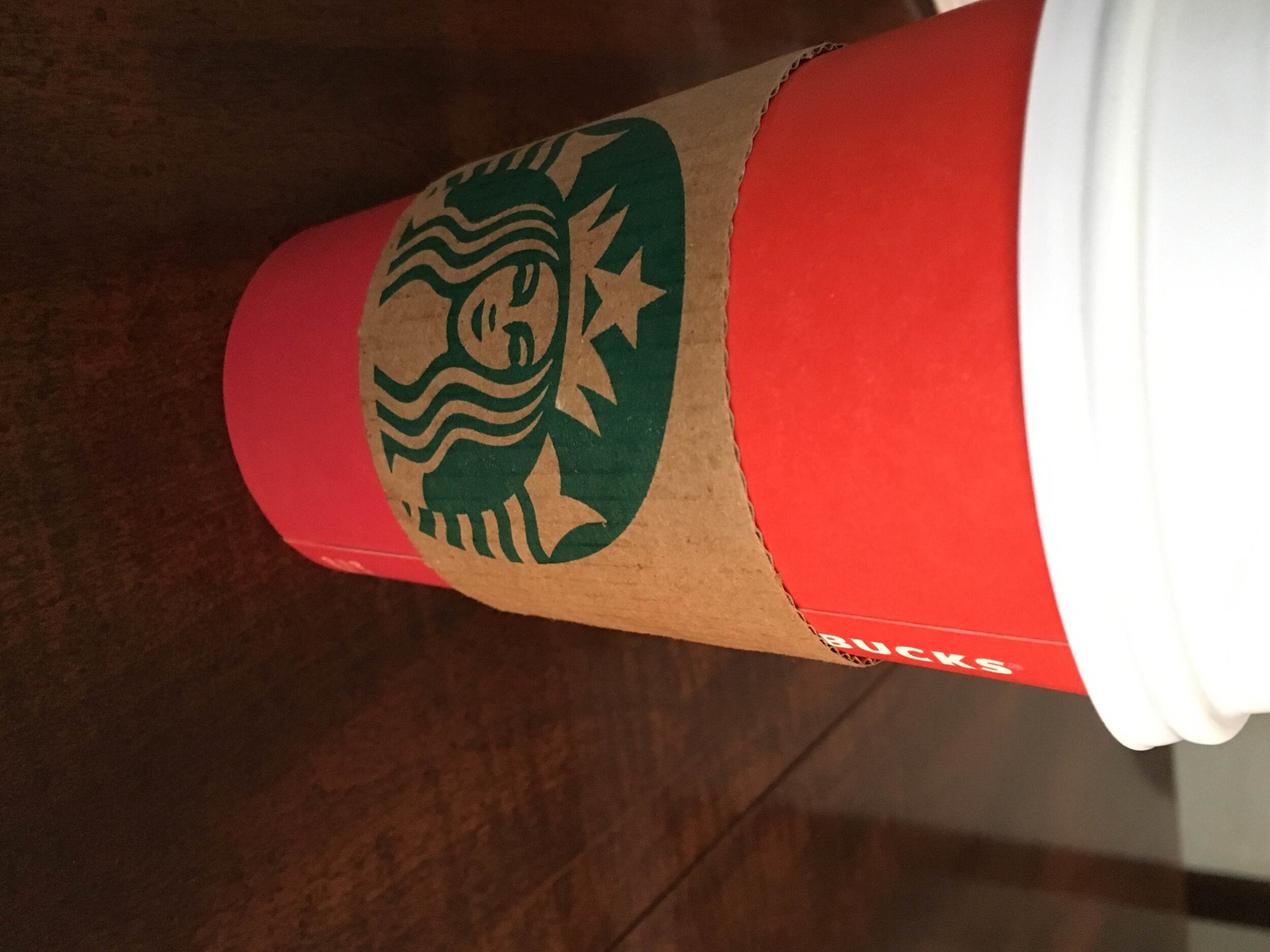 close up of starbucks red cup sitting on dark wood table
