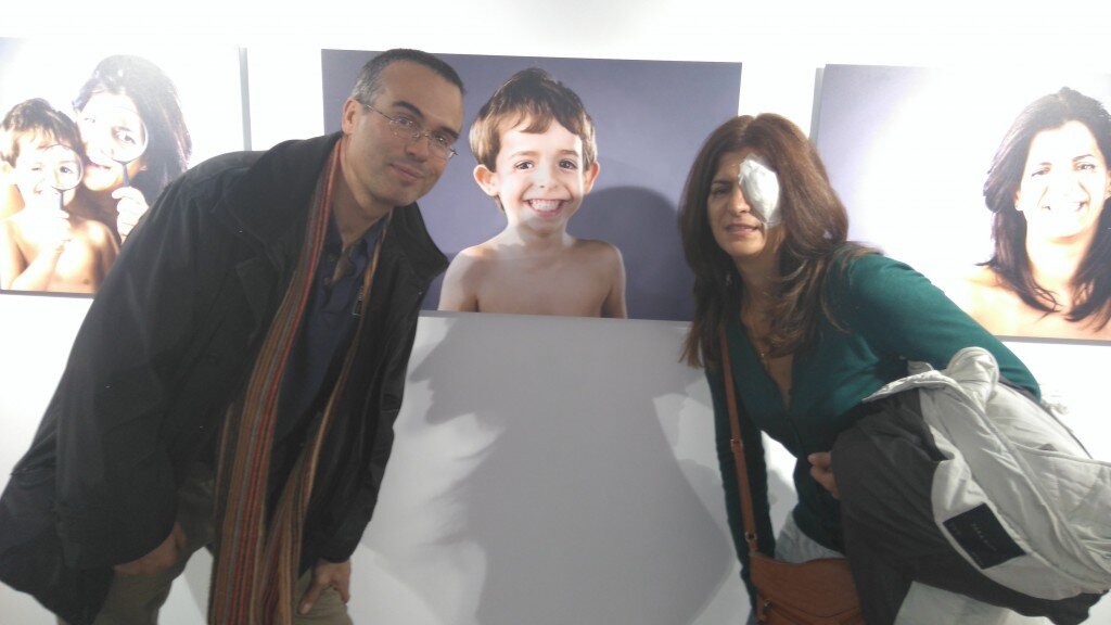 Susana Lázaro junto a su marido y una fotografía de su hijo expuesta en "Quiero cinco sentidos", de la Fundación ONCE
