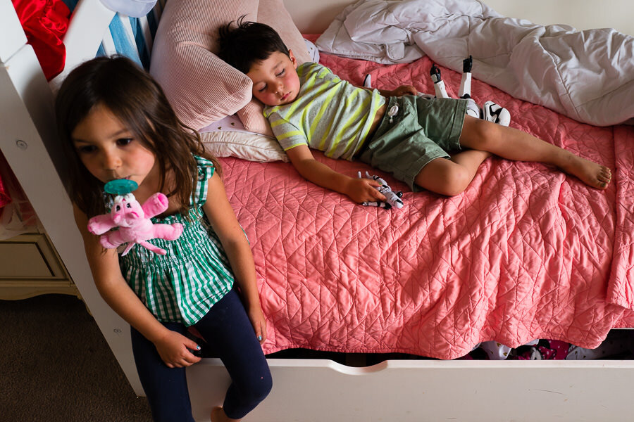A boy asleep in his bed while a girl has a pacifier in her mouth