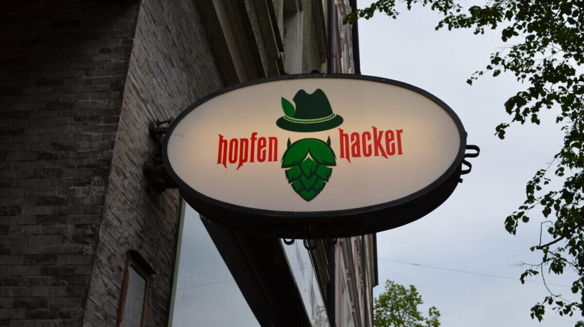 A picture of the Hopfenhäcker bar sign lit up in Munich