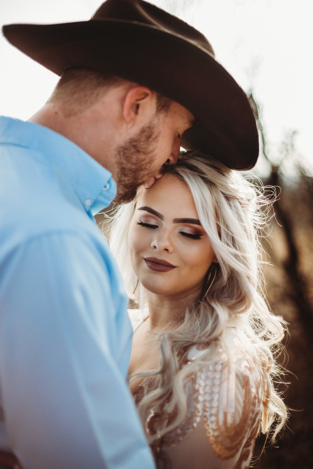  Lighting photo of sunset through her hair and focusing no a kiss on the forehead and black cowboy hat #engagementphotos #engaged #personality #amarillotexas #engagementphotographer #lifestylephotos #amarillophotographer #locationchoice #texasengagementphotos #engagment #tealawardphotography #westernstyle 