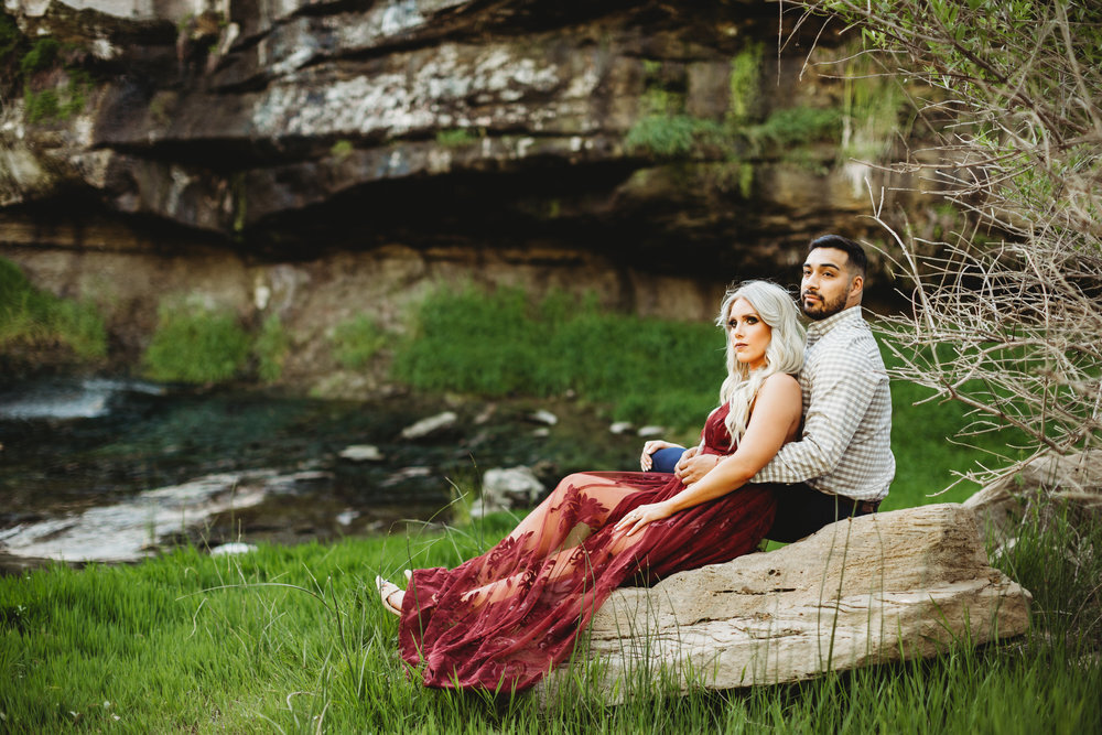  Sitting in the wildlife refuge together with green foliage in the background in ruby red dress #engagementphotos #riverfalls #engaged #personality #amarillotexas #engagementphotographer #lifestylephotos #amarillophotographer #locationchoice #texasengagementphotos #engagment #tealawardphotography #wildliferefuge 
