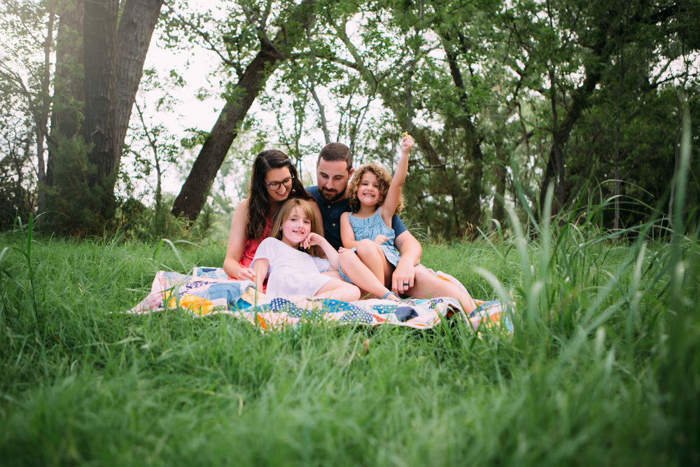  Family sitting on picnic blanket in green grass with greenery from trees behind them #tealawardphotography #texassummerphotographer #pictureseason #amarillophotographer #amarillofamilyphotographer #emotionalphotography #engagementphotography #couplesphotography #pickingaseasonforphotosessions #whatsimportant #everythingtogether #pickingcolorsforphotos #summerphotos #greeneryinphotos 