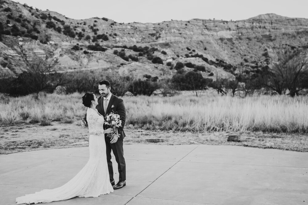  Black and white photo of the bride in her lace dress and the groom in Palo Duro Canyon, Texas #tealawardphotography #texasweddings #amarillophotographer #amarilloweddingphotographer #emotionalphotography #intimateweddingphotography #weddingday #weddingphotos #texasphotographer #inspiredwedding #intimatewedding #weddingformals #bigday #portraits 