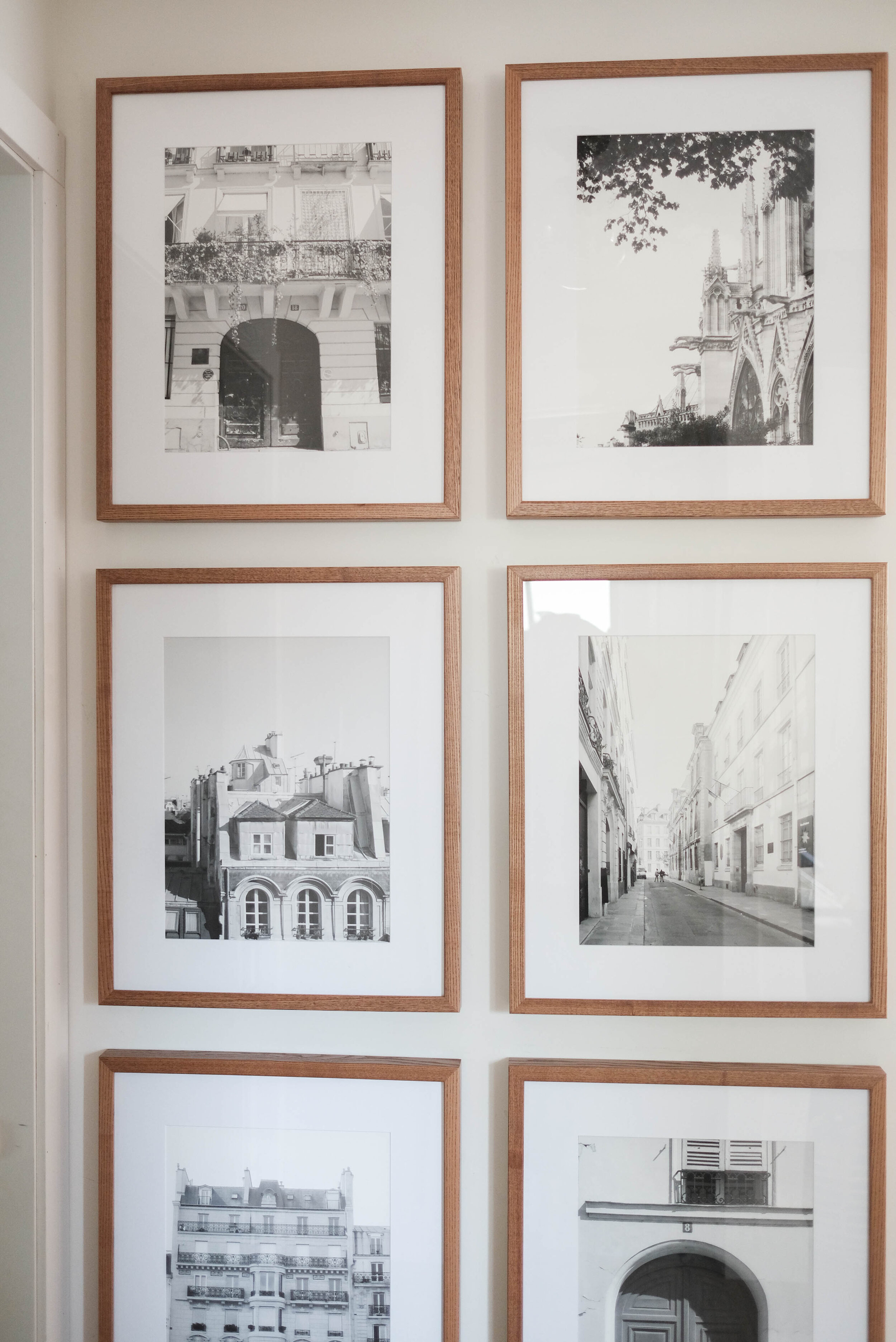 Symmetrical gallery wall in a hallway with light walnut frames from PosterJack. 