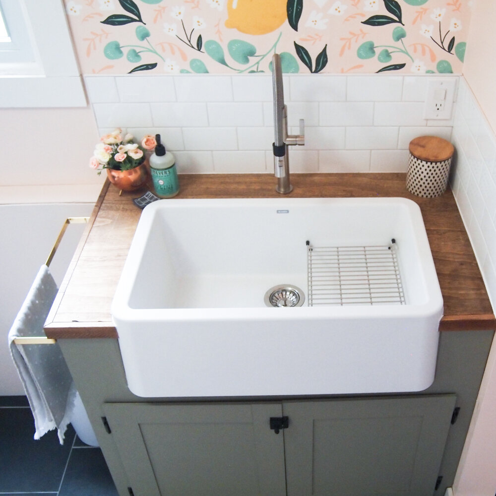 view from above: white apron front sink, green cabinet, fake butcher block countertop, lemon wallpaper