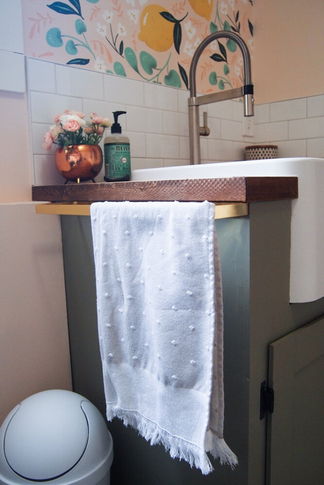 corner of sink, gold towel bar, green cabinet, apron front sink
