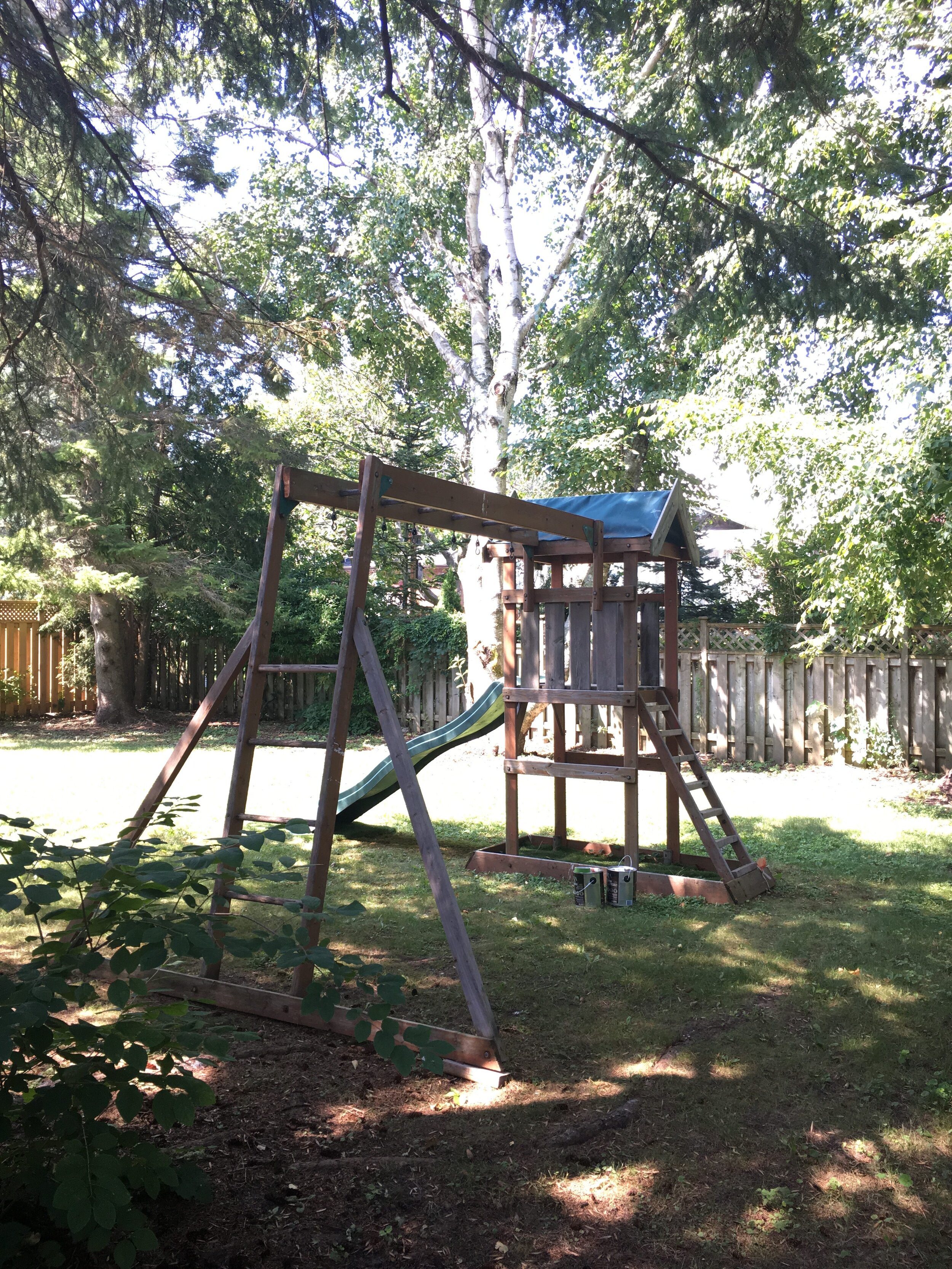 Olds kids' play set in the shade of a backyard